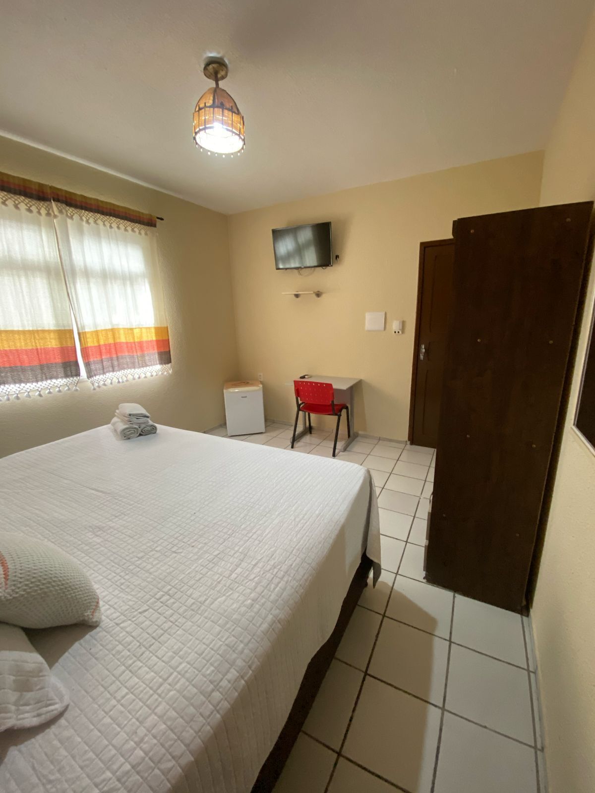 Une chambre d’hôtel équipée d’un lit, d’un bureau, d’une télévision et d’une armoire.