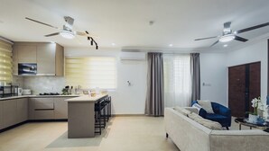 Una cocina moderna con una isla central, un comedor y una sala de estar con un sofá y un sillón azul.