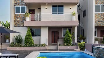 Un hôtel moderne doté d’une piscine, de nombreux balcons et d’un espace extérieur aménagé pour s’asseoir.