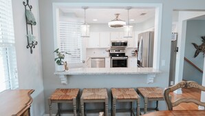 A modern kitchen with white cabinets, stainless steel appliances, and a central island with stools.