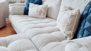 A beige sofa with a textured fabric and a decorative pillow with a starfish design.