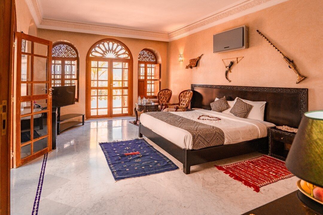 Une chambre avec un grand lit, une télévision et des éléments décoratifs accrochés aux murs.