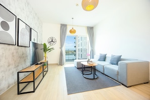 A modern living room with a sofa, a coffee table, a TV, and artwork on the wall.