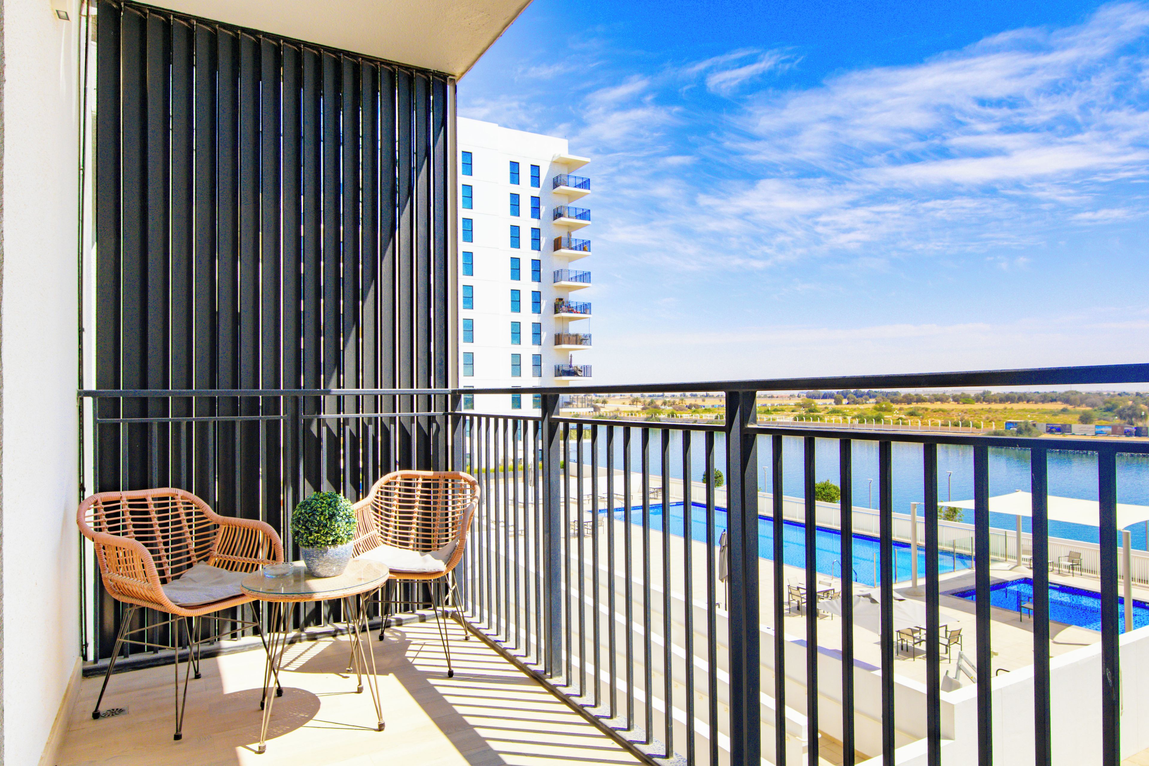A balcony with two wicker chairs, a small table, and a potted plant.