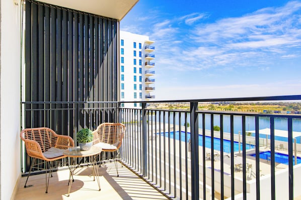 A balcony with two wicker chairs, a small table, and a potted plant.