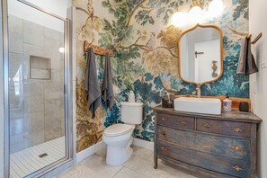 Un bagno con doccia, WC, lavabo e uno specchio decorativo.