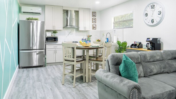 A modern kitchen with white cabinets, a stainless steel refrigerator, and a dining area with a wooden table and chairs. - Cozy & Stylish Apartment for 4 just 5 Minutes from Downtown (Mount Dora)