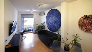 En moderne stue med en mørk sofa, et glasbord og to plantede planter.