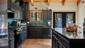 A modern kitchen with dark cabinetry, a stainless steel stove, and a large island.