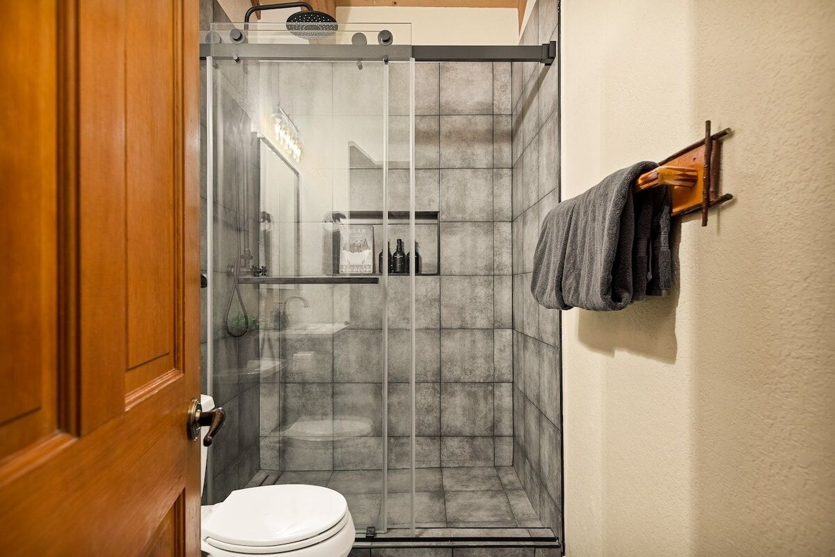 A shower with a glass door, a toilet, and a towel rack with towels.