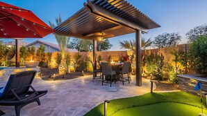 A patio with outdoor furniture, a pergola, and a well-lit garden area. - 7BR/4BATH Escape w/HEATED Pool, Billiards, Arcade Room, Hot Tub & Mini Golf (Peoria)