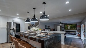 A modern kitchen with a large island, bar stools, and pendant lighting. - 7BR/4BATH Escape w/HEATED Pool, Billiards, Arcade Room, Hot Tub & Mini Golf (Peoria)