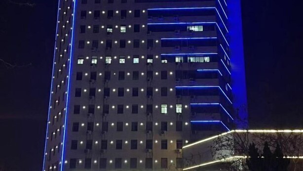 A high-rise building with multiple floors, each illuminated by white lights.