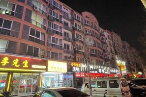 A multi-story building with illuminated signage, a parked van, and a car in front.