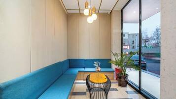 A modern interior with a blue sofa, a round table, and a potted plant.