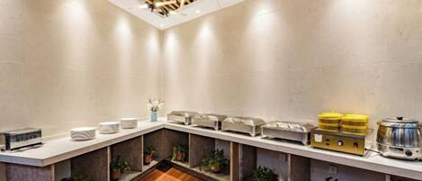 A modern kitchen with a long counter, built-in appliances, and potted plants.