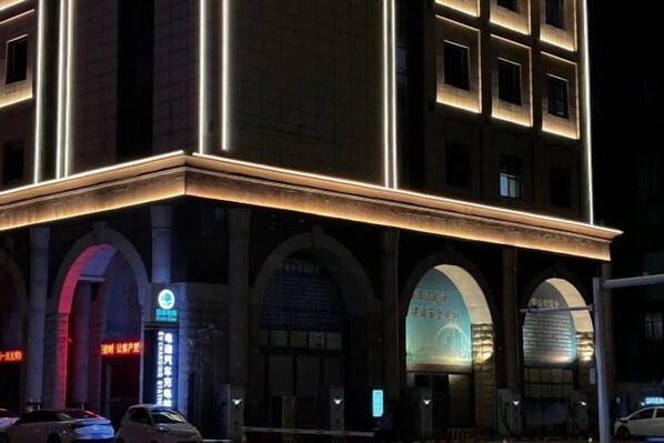Un edificio de varios pisos con señalización iluminada y ventanas arqueadas.