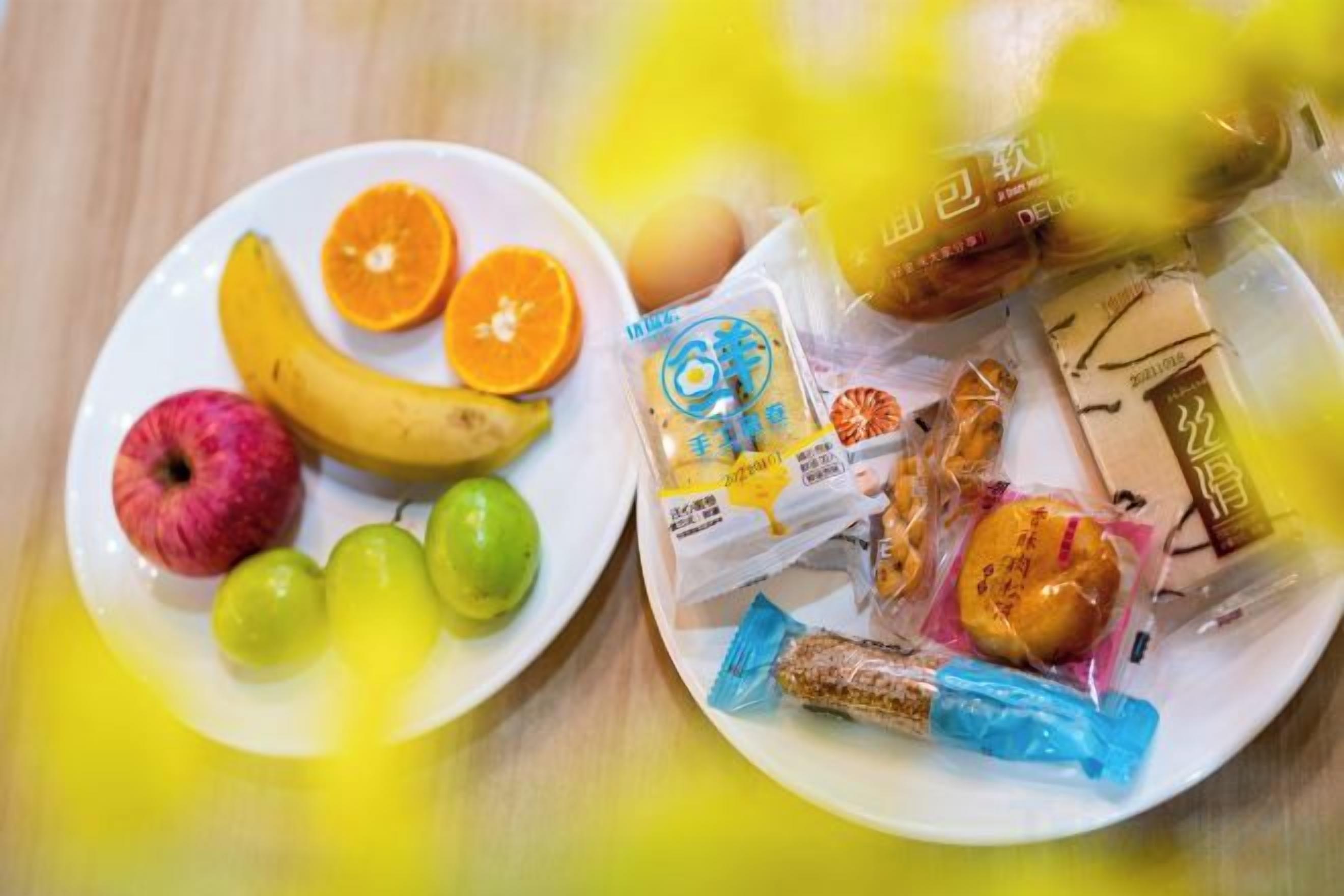 A plate with fruits and packaged snacks.