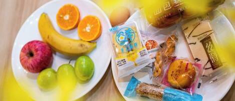 A plate with fruits and packaged snacks.