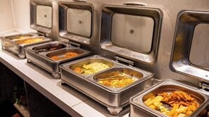 Un buffet proposant une variété de plats présentés dans des récipients en acier inoxydable.