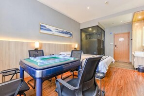 A hotel room with a bed, a desk with a laptop, a chair, a table with a board game, and a painting on the wall. - Jingman Light Luxury Hotel (Shangqiu Experimental Middle School High-speed Railway Station) (Shangqiu)