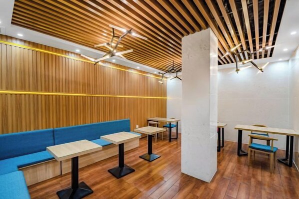 A modern interior with wooden panel walls, a blue seating area, and tables with chairs. - Jingman Light Luxury Hotel (Shangqiu Experimental Middle School High-speed Railway Station) (Shangqiu)