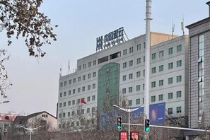 Een meerlaags gebouw met een groen luifel en een bord met Chinese karakters.
