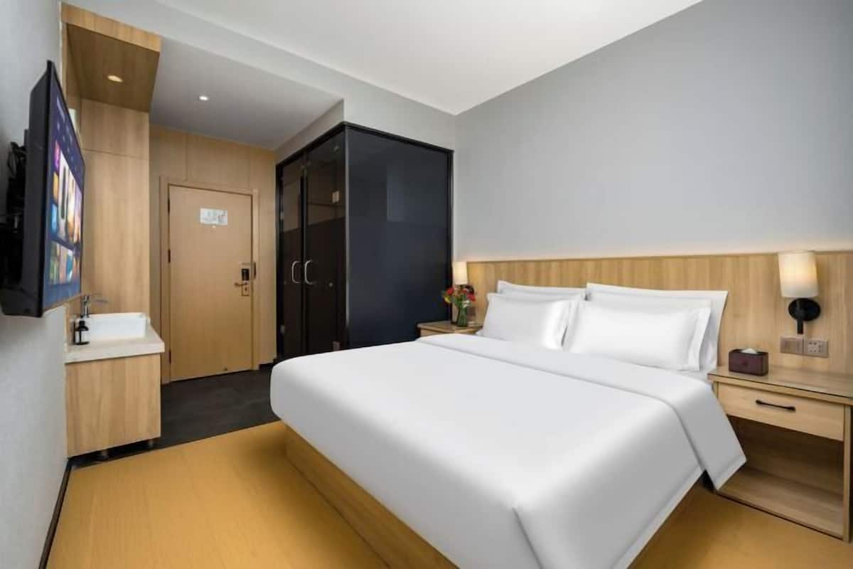 Une chambre d’hôtel comprenant un lit, des tables de chevet, une télévision, une armoire et une salle de bain.
