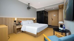 Une chambre d’hôtel moderne dotée d’un grand lit, de tables de chevet, d’un petit bureau, d’une chaise, d’une table ronde et d’une armoire.