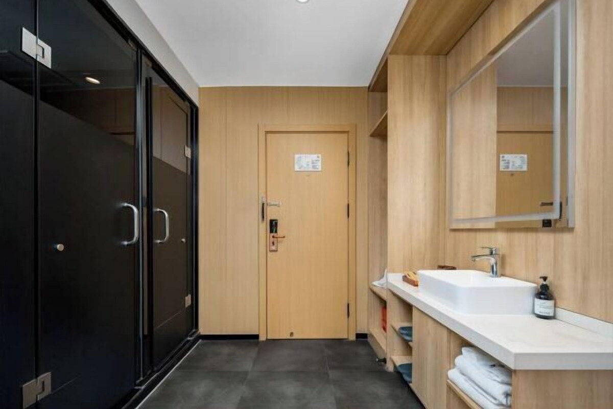 A modern bathroom with a wooden door, a white sink, and a mirror.