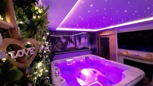 Een kamer met een jacuzzi, een sterrenhemel aan het plafond en een 'LOVE' bord.
