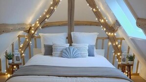 Een gezellig slaapkamer op zolder met een groot bed, lichtjes en een houten plafond.