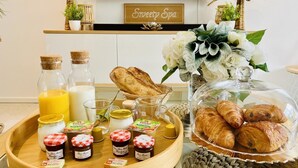 Een ontbijtbuffet met brood, gebak en toevoegingen op een houten dienblad.