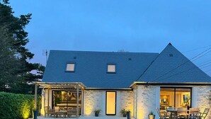 Een huis met een stenen gevel, een schuin dak en een overdekte patio met tuinmeubilair.