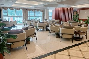 Eine Hotelhalle mit mehreren Sitzbereichen, großen Fenstern und einem modernen Innenraum.