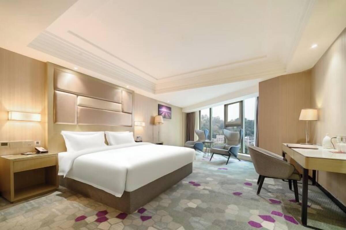A hotel room with a large bed, bedside tables, a desk, and a chair.
