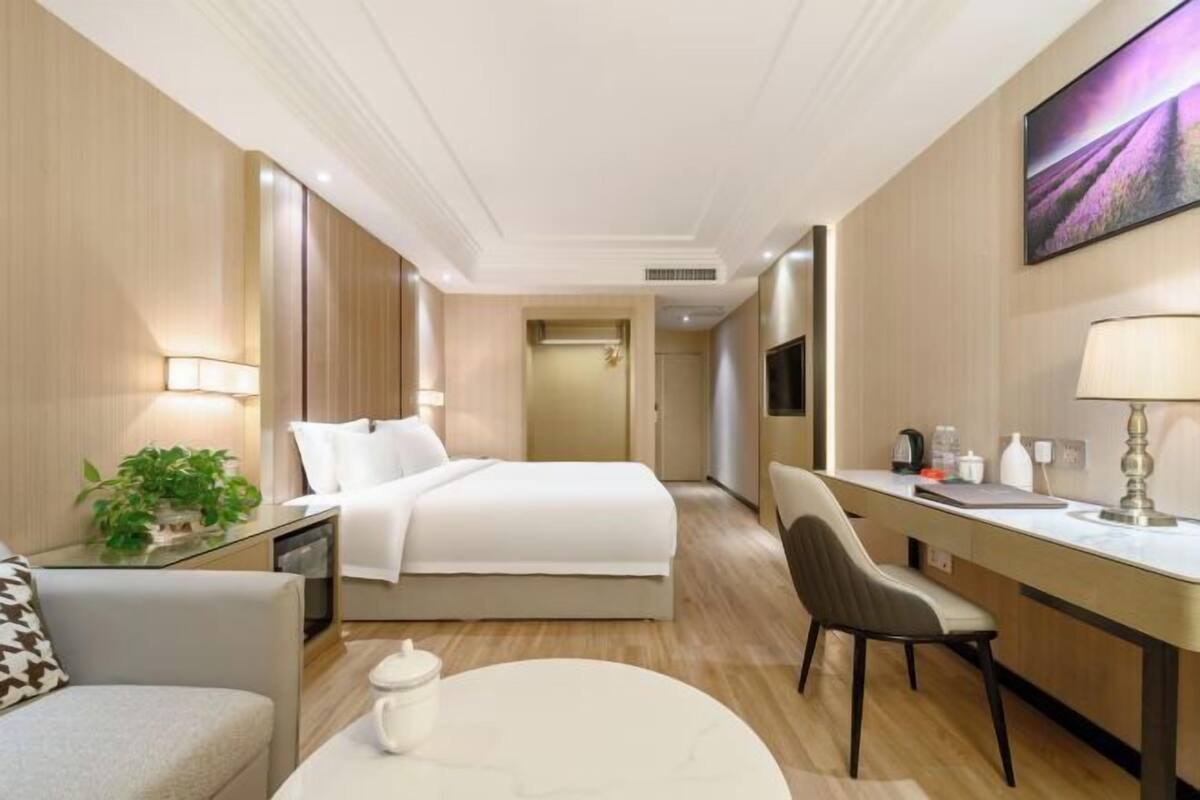 A hotel room with a bed, desk, chair, and a TV.