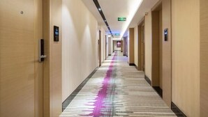 A hotel corridor with wooden doors, a patterned carpet, and a ceiling with recessed lighting. - Lavande Hotel (Suining Heping West Road) (Suining)