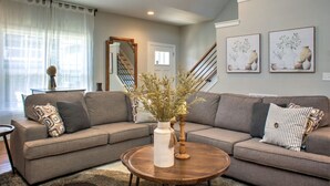 A living room with a sectional sofa, a round coffee table, and a vase with dried plants. - 4 Kings Walkable to Lake Louise. (Weaverville)