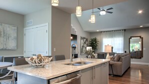 A modern kitchen with a granite countertop, stainless steel appliances, and a bowl of seafood on the island. - 4 Kings Walkable to Lake Louise. (Weaverville)