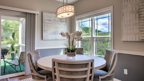 A dining area with a round table, chairs, a hanging light fixture, and a view through large windows. - 4 Kings Walkable to Lake Louise. (Weaverville)
