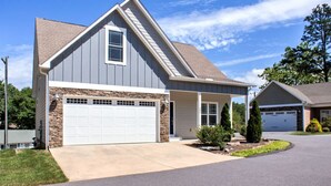 A two-story house with a garage, a stone foundation, and a covered front porch. - 4 Kings Walkable to Lake Louise. (Weaverville)