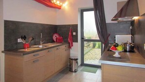 A kitchen with wooden cabinets, a sink, and a stove. - Gîtes de France® - Le Petit Marin (BRUNVILLE)
