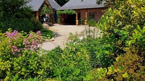 A rustic lodge with two thatched-roof cabins, surrounded by lush greenery and flowering plants. - Gîtes de France® - Le Petit Marin (BRUNVILLE)