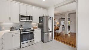 Una cucina moderna con mobili bianchi, elettrodomestici in acciaio inossidabile e zona pranzo in legno.