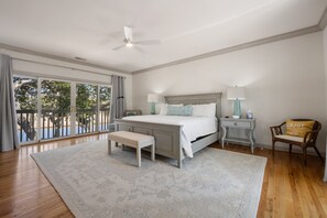 Une chambre avec un grand lit, un banc, une table de chevet, une chaise et une vue sur l’extérieur grâce à une porte coulissante.