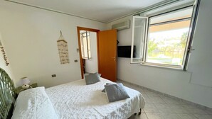 A bedroom with a bed, a window, and a door.