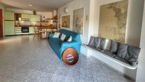 A spacious living area with a sofa, a dining table, and a kitchen in the background.