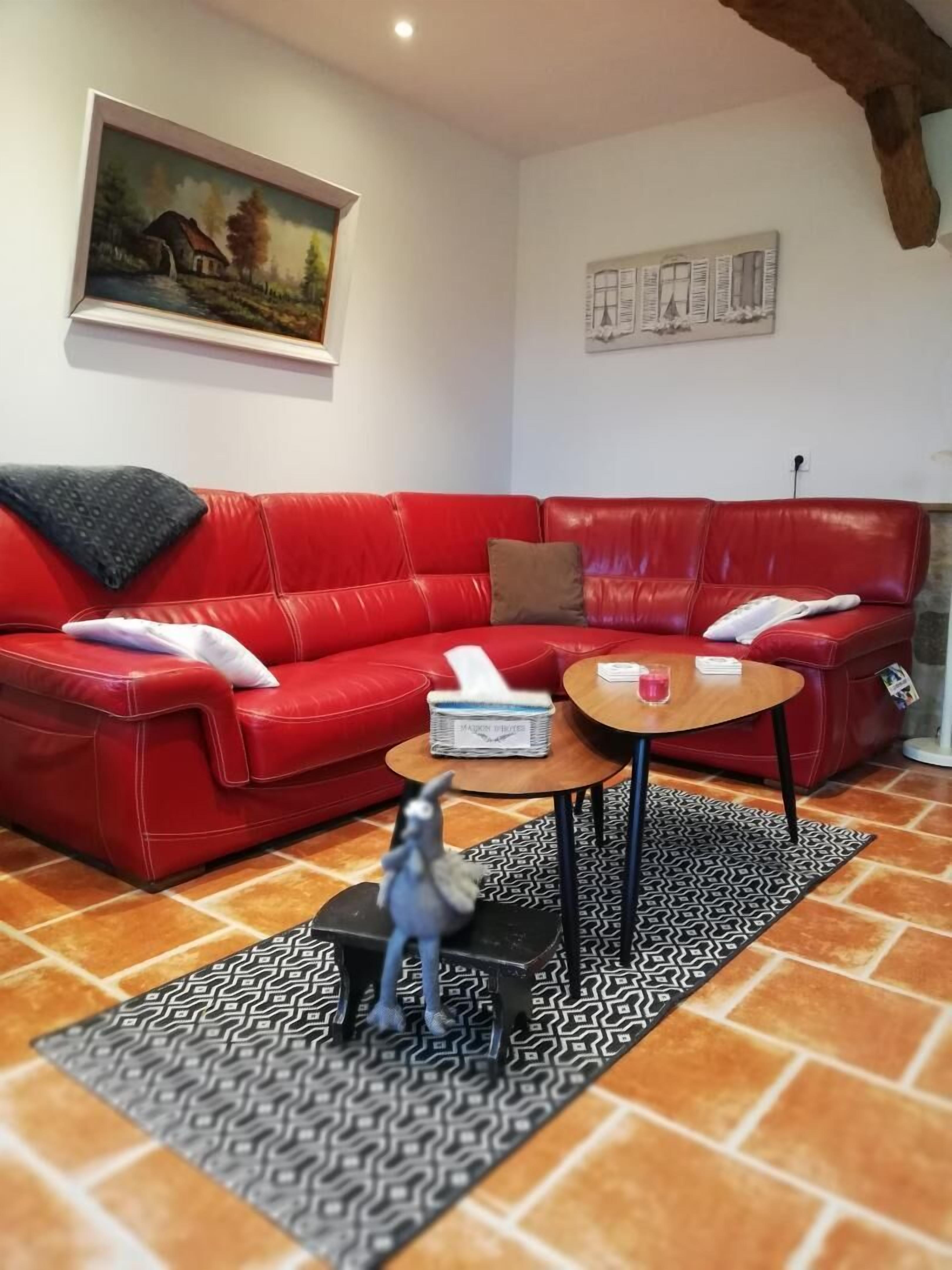 Ein rotes Ledersofa, ein kleiner Holztisch und ein gemustertes Teppich in einem Wohnzimmer mit einem Bild an der Wand.