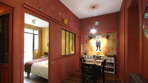 Une pièce comprenant un lit, une table à manger avec des chaises, un miroir et une horloge au mur.